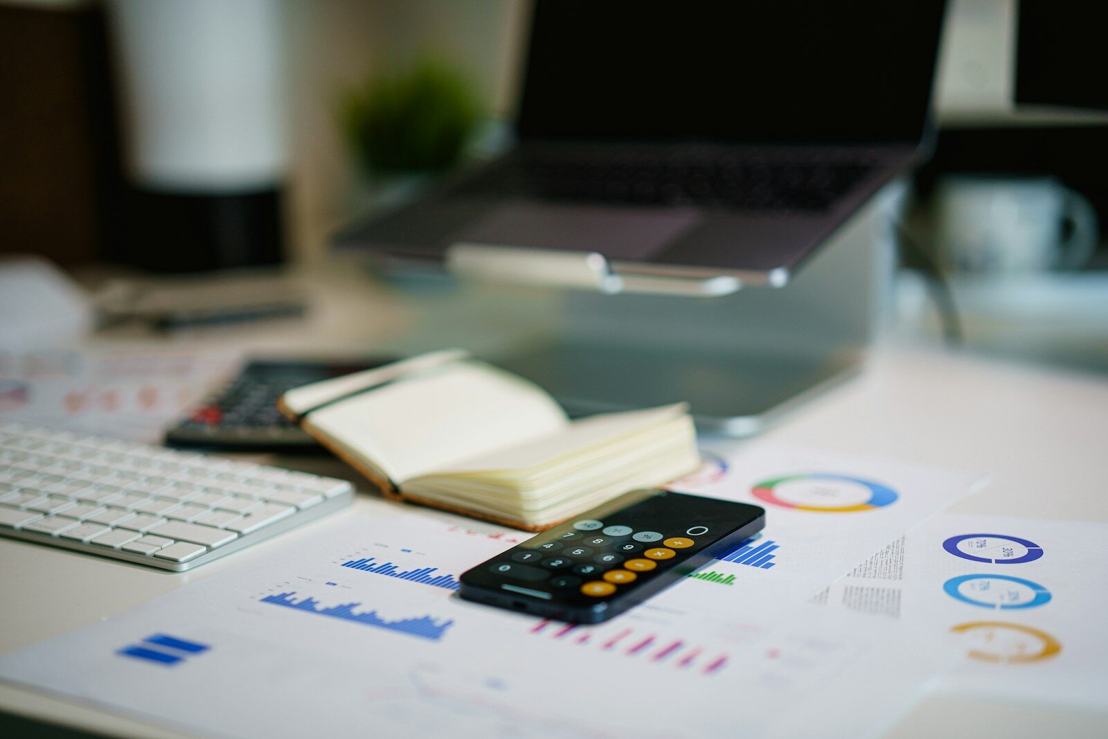 Accounting time a phone calculator and papers on table next to a laptop