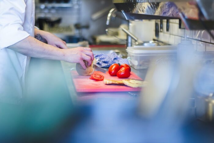 Photo by Louis Hansel person slicing tomatoes